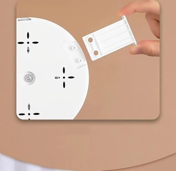 White wall socket cover with a hand holding a white plastic component on a beige background