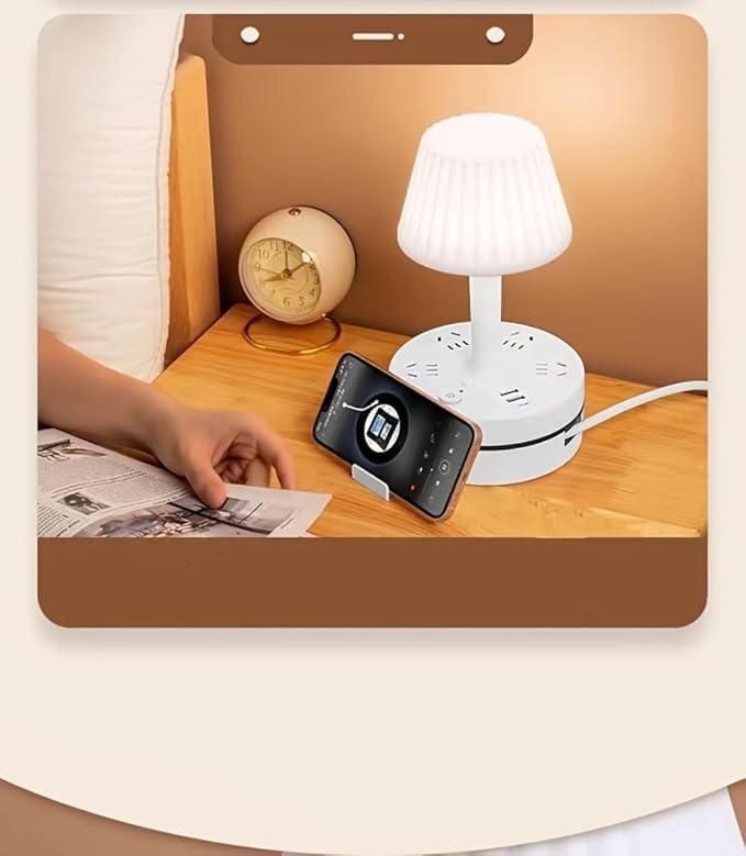 Small white lamp on a wooden desk with a phone and clock in the background