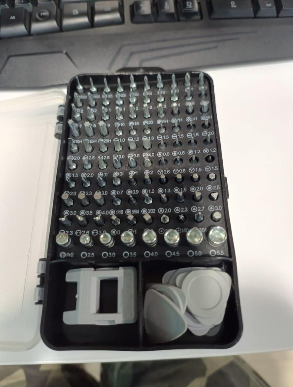 Set of guitar picks in a case on a desk with a keyboard in the background