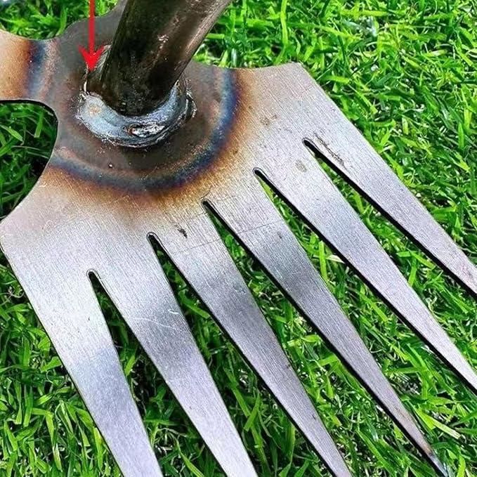 Metal garden fork on grass with a red arrow pointing to a worn area.