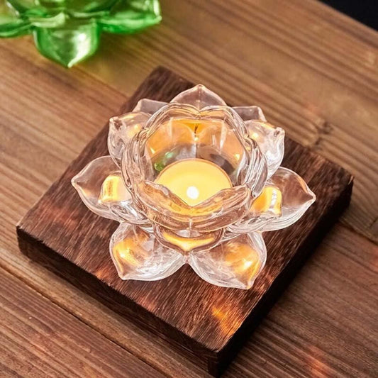 Glass lotus flower candle holder with a candle on a wooden base