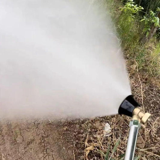 Garden hose nozzle spraying water on a patch of soil with grass in the background