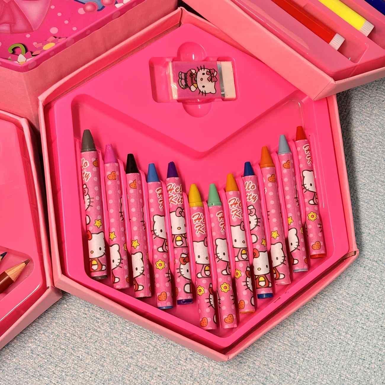 Pink Hello Kitty crayon set with various colored crayons and a pink box on a gray surface.