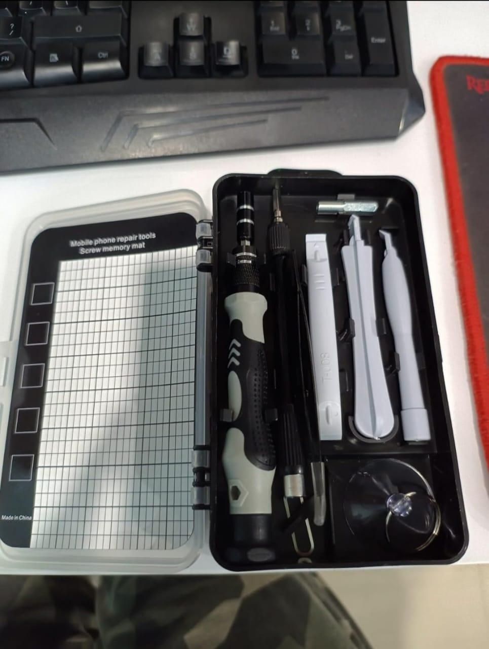 Set of electronic repair tools in a case on a white surface with a keyboard in the background.