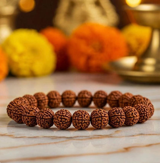 Brown beaded bracelet on a marble surface with blurred decorative items in the background
