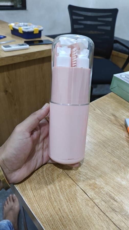 Pink travel mug with a straw on a wooden desk