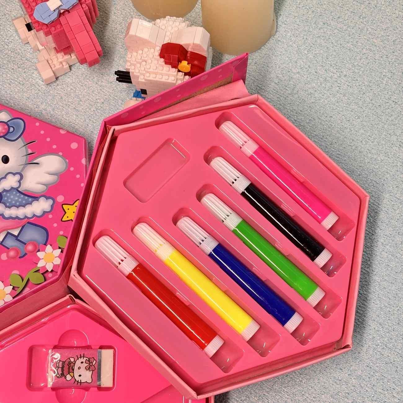 Pink art set with markers and a Hello Kitty design on a gray surface
