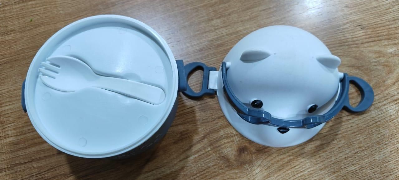 White lunch container with blue handle and lid on a wooden surface
