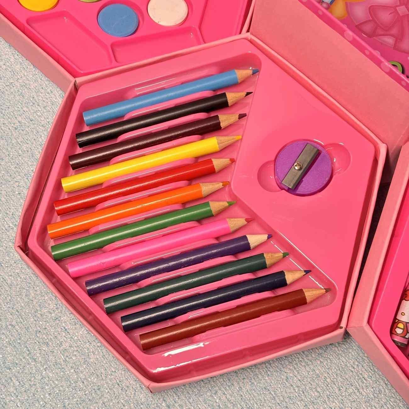 Set of colorful pencils in a pink case with a sharpener on a gray surface