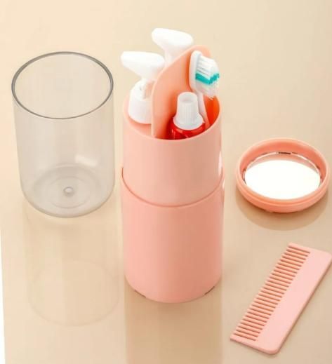 Pink toothbrush holder with toothbrushes, clear glass, and pink comb on a beige background